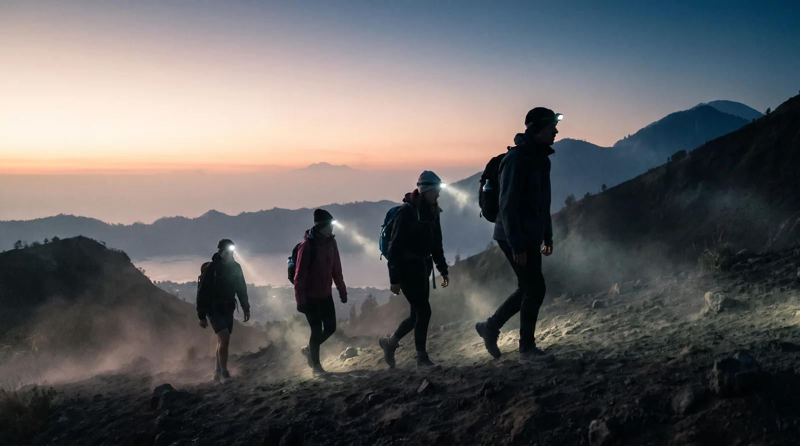 Group of hikers ascending a Bali volcano trail before sunrise