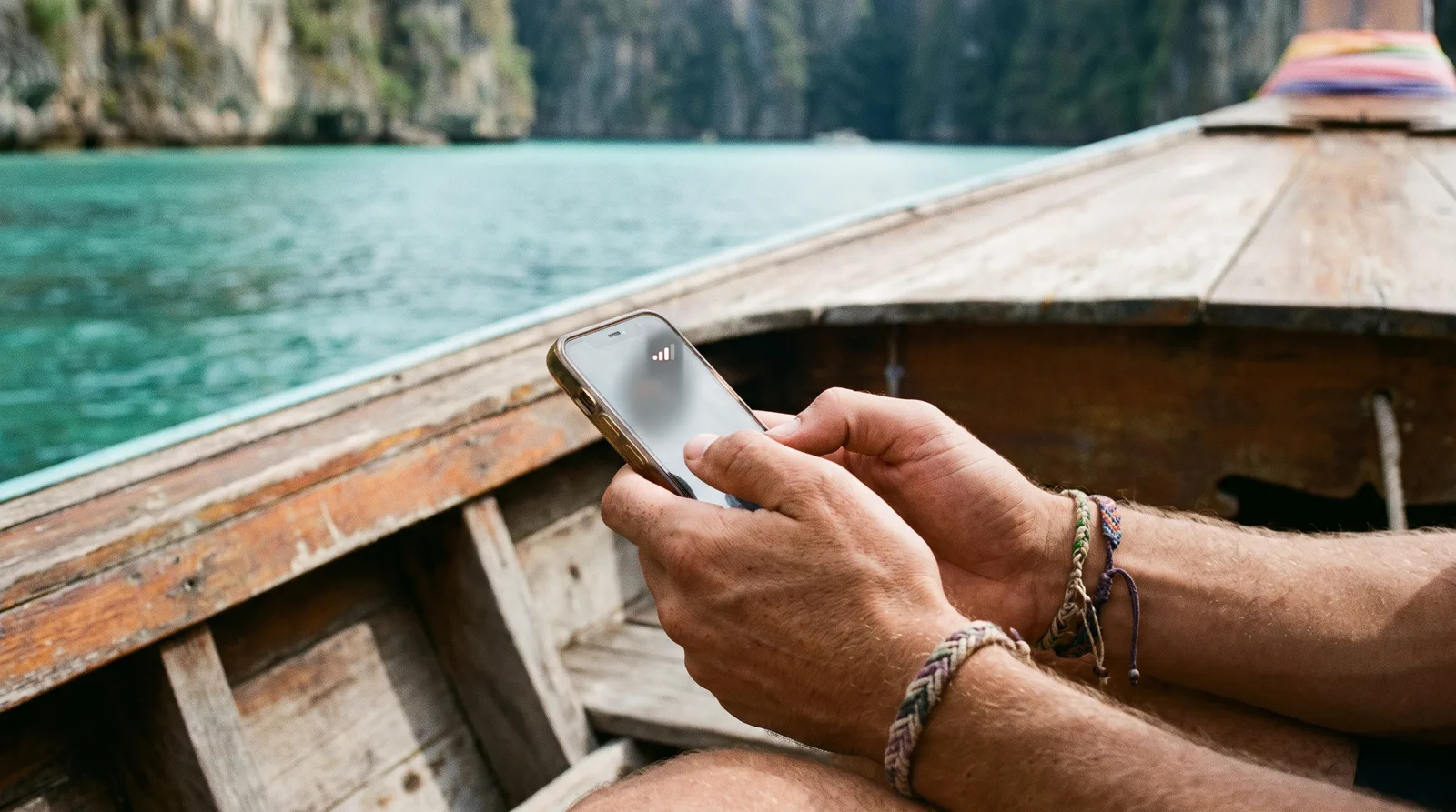 Traveller checking phone signal on a longtail boat near a Thai island
